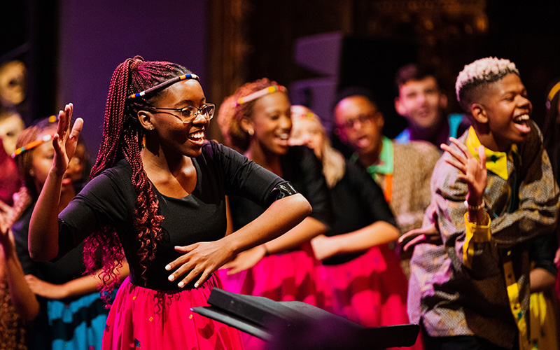 Solozangeres van UP Youth Choir danst en zingt vooraan op het podium van de Bourlaschouwburg